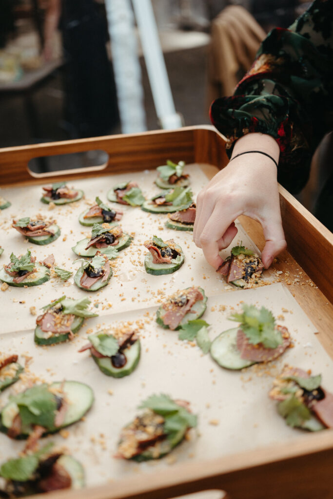 Tray of canapes with sliced meat and herbs on cucumber