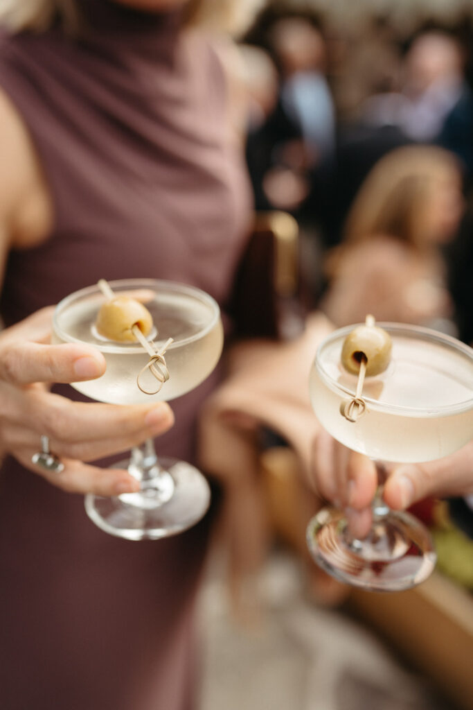 Two guests holding martinis garnished with olives