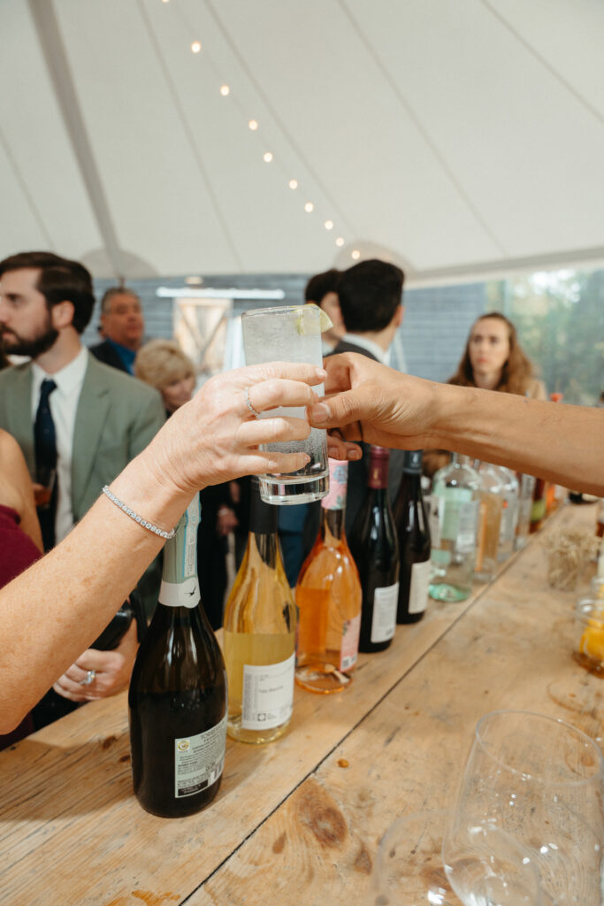 Hands raising glasses at a bar lined with wine bottles