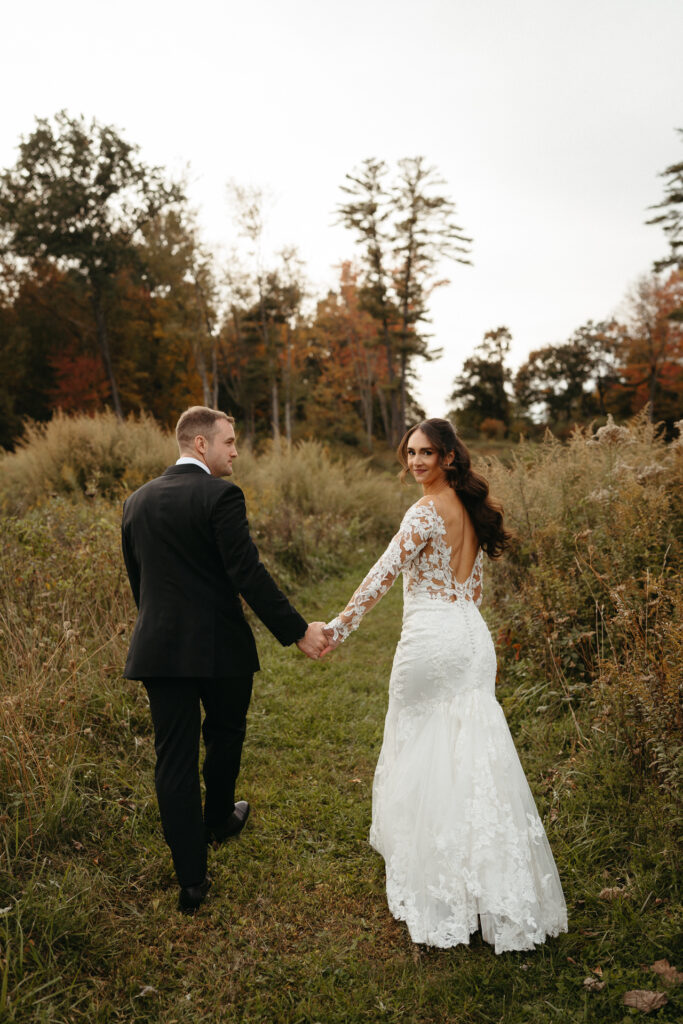 Couple walking hand in hand through a field, seen from behind