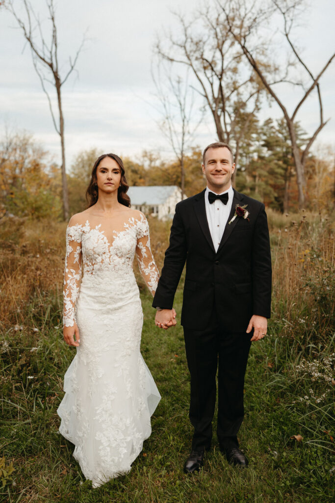 Couple holding hands and facing the camera in a meadow