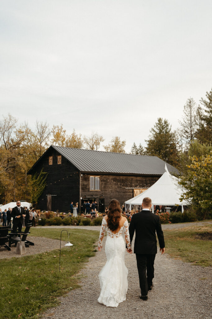 Couple walking down a gravel path toward the barn and tent