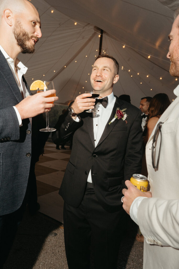Guests laughing and holding drinks under the tent