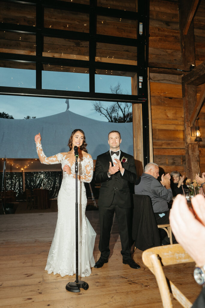 Person at the microphone with an arm raised, their partner beside them