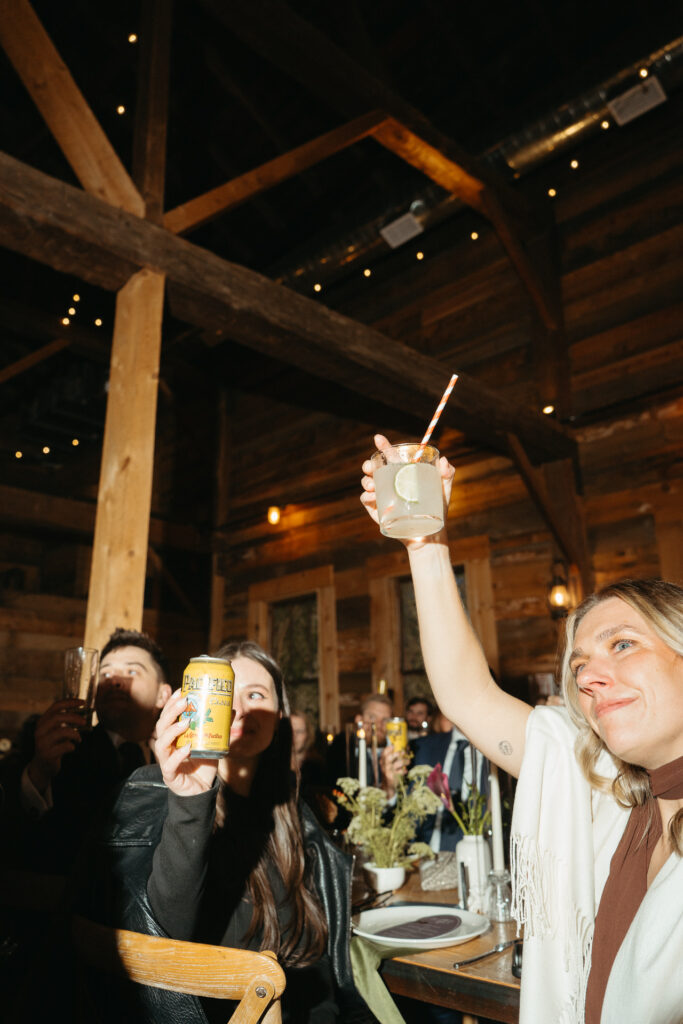Guest raising a drink at a table in the barn