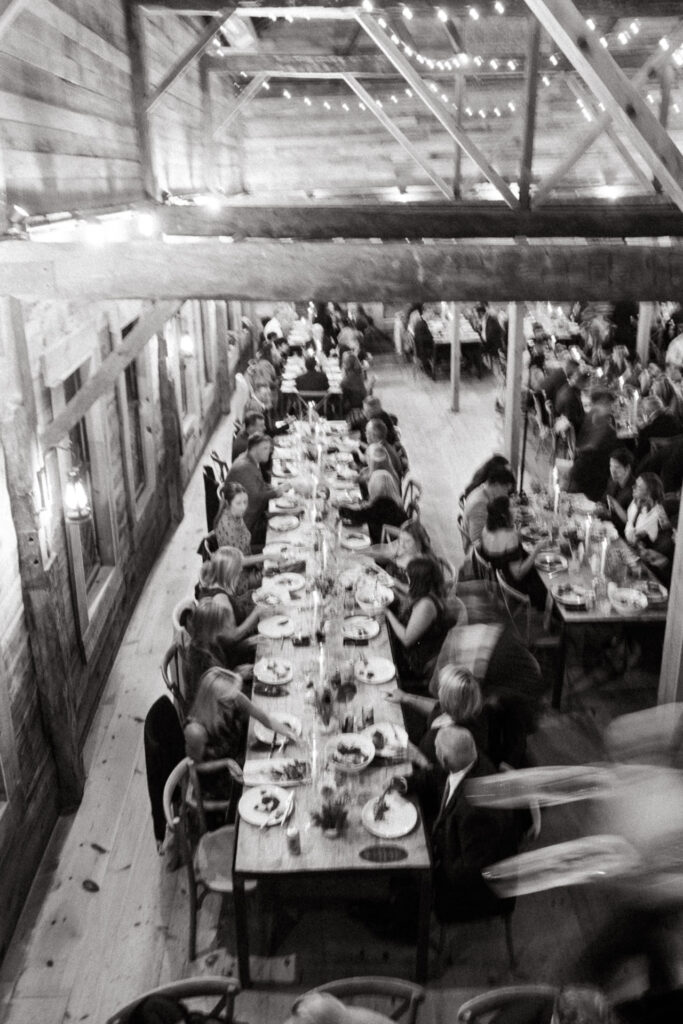 Black and white view of a long barn table full of guests