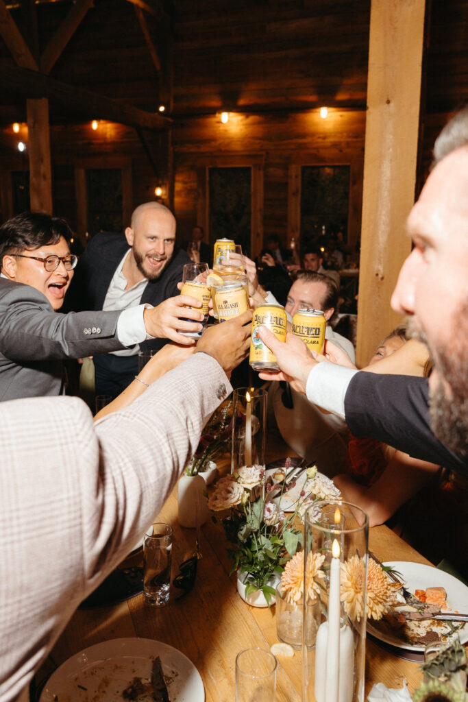 Guests clinking cans and glasses over a table