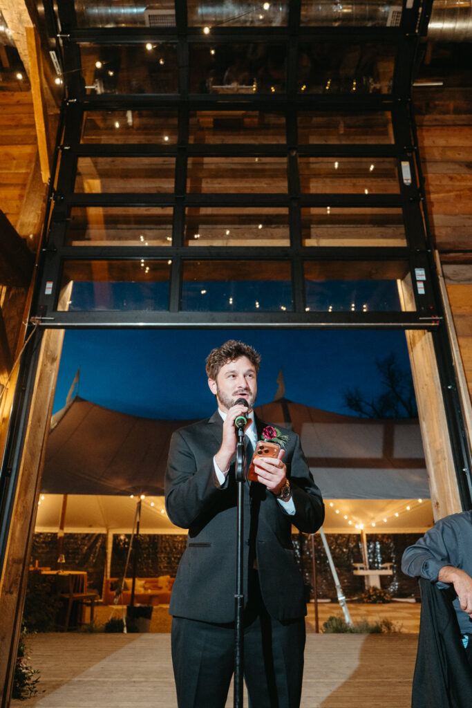 Person in a suit giving a toast at a microphone