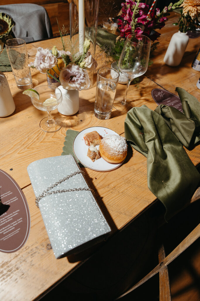 Table with flowers, a glittery clutch and a doughnut