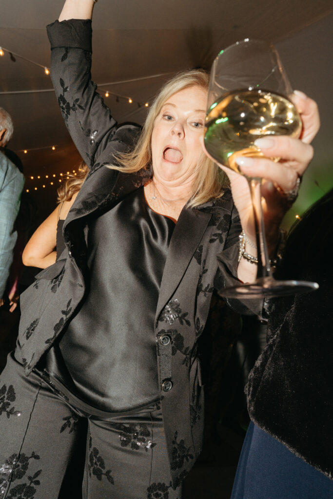 Guest in a dark suit holding up a glass of white wine on the dance floor