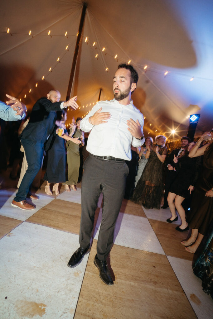 Guest in a white shirt lifted by another guest on the checkered dance floor