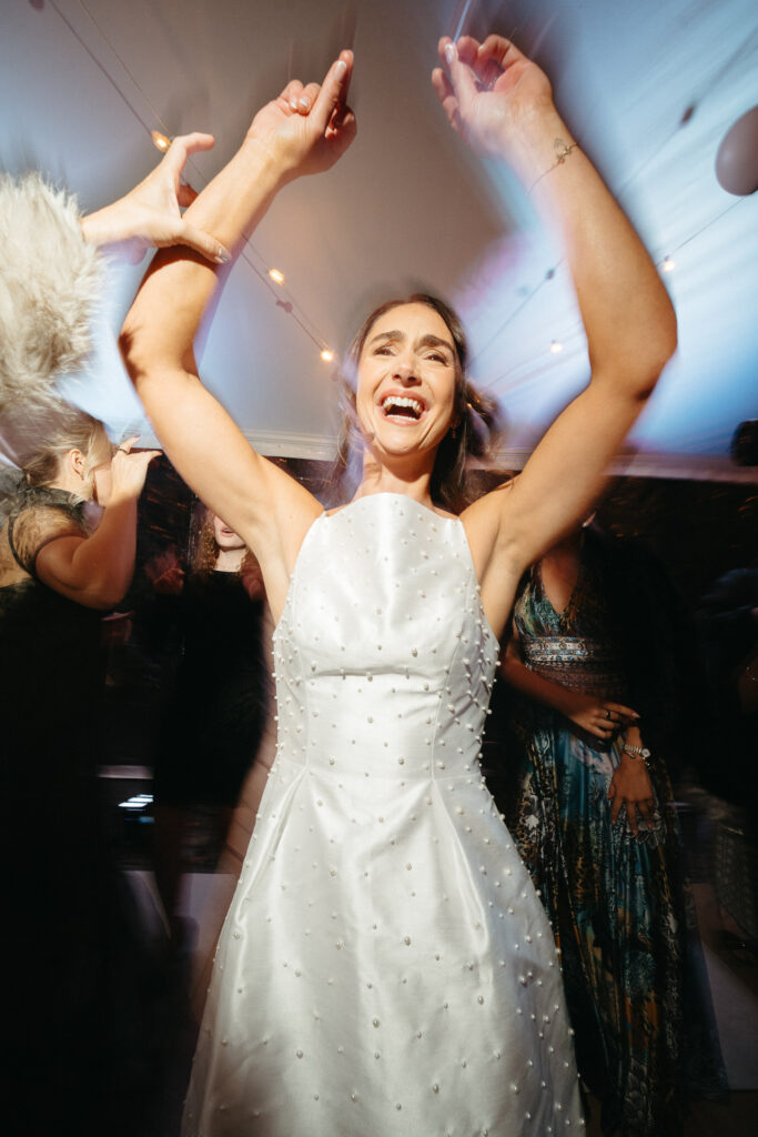 Person in a white dress dancing with arms overhead