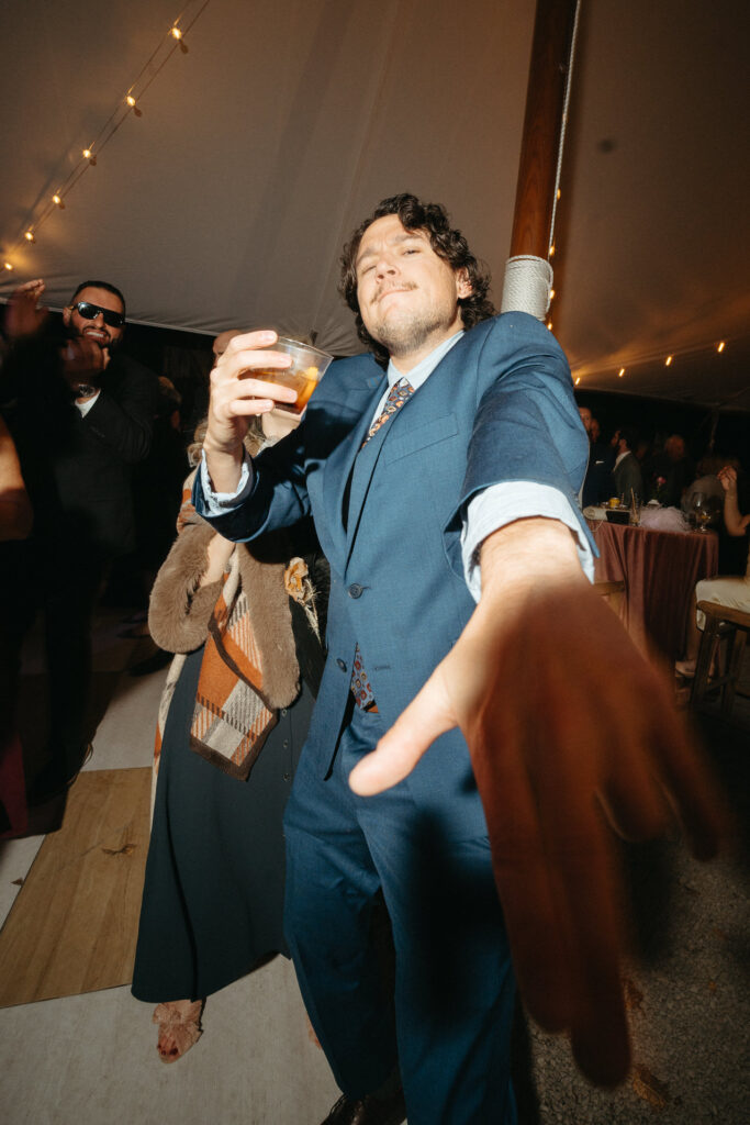 Guest in a navy suit dancing with a drink in hand