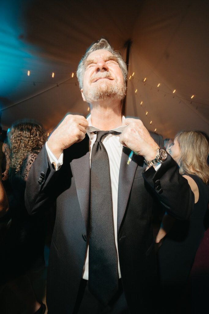 Guest in a suit tugging at their tie while dancing