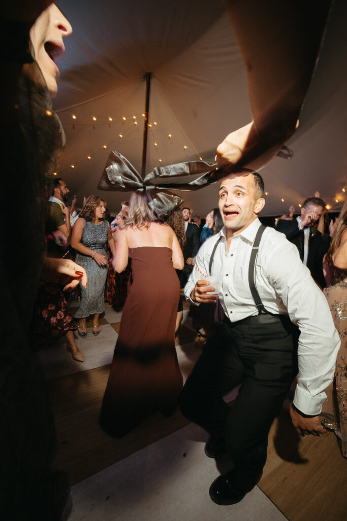 Guest in suspenders dancing near a bow-shaped napkin overhead