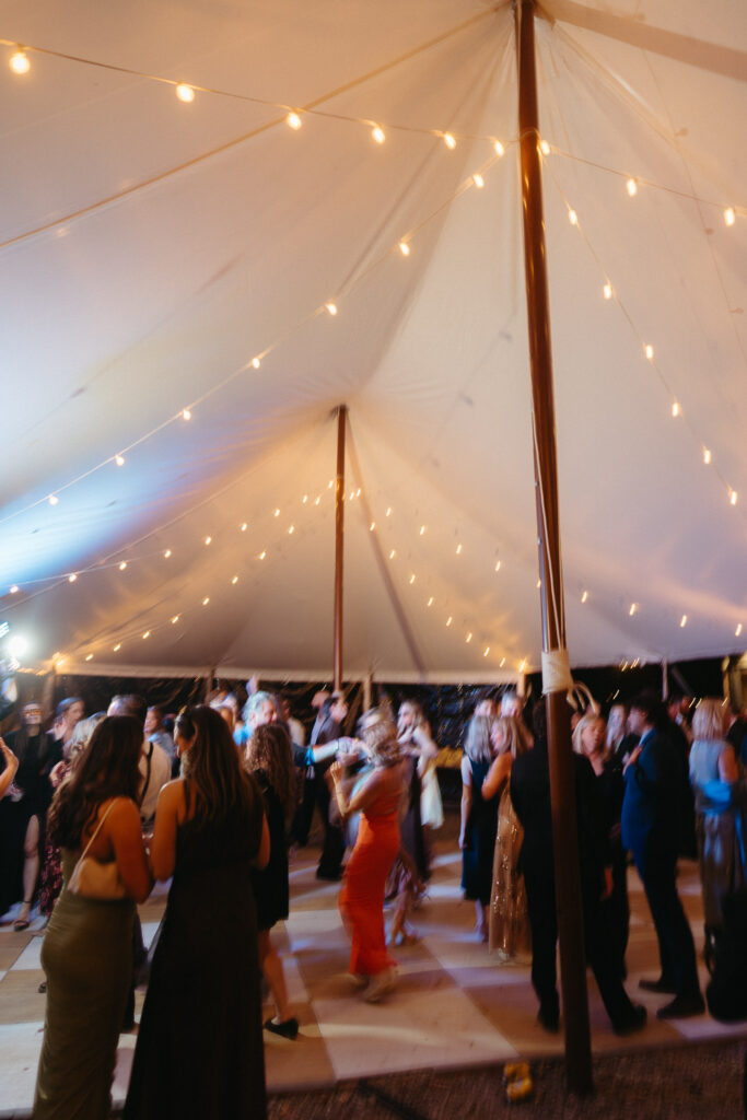 Crowd dancing on a checkered floor under string lights