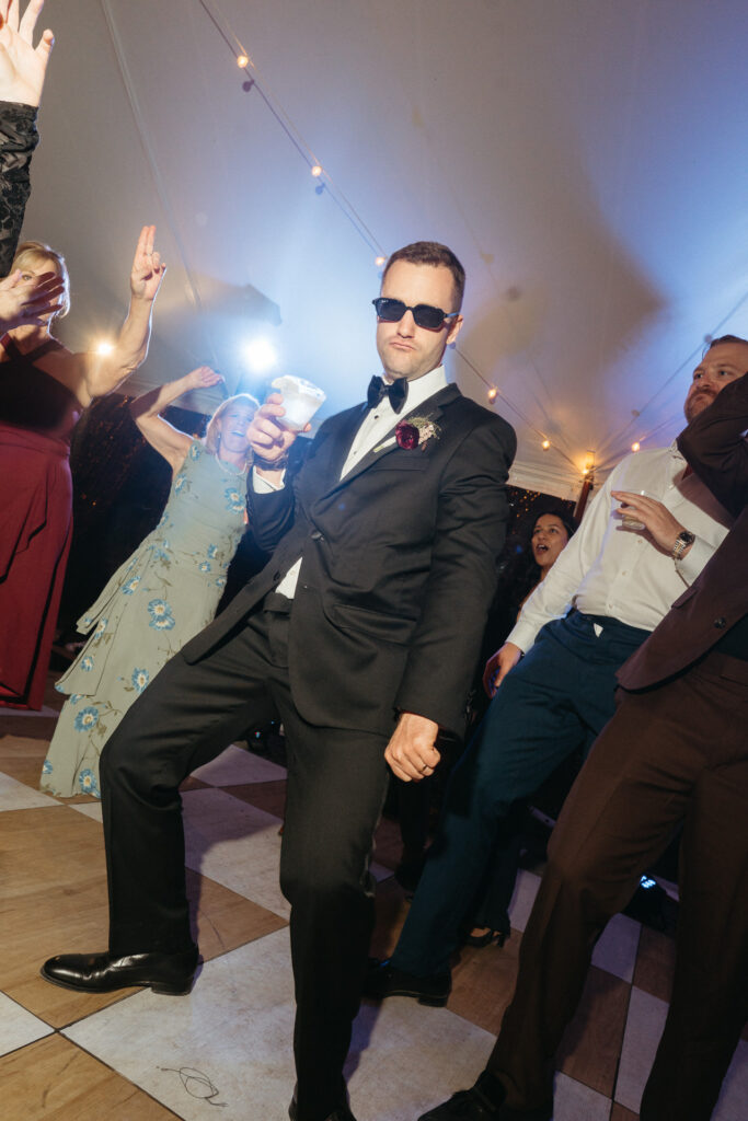 Person in sunglasses and a tuxedo dancing
