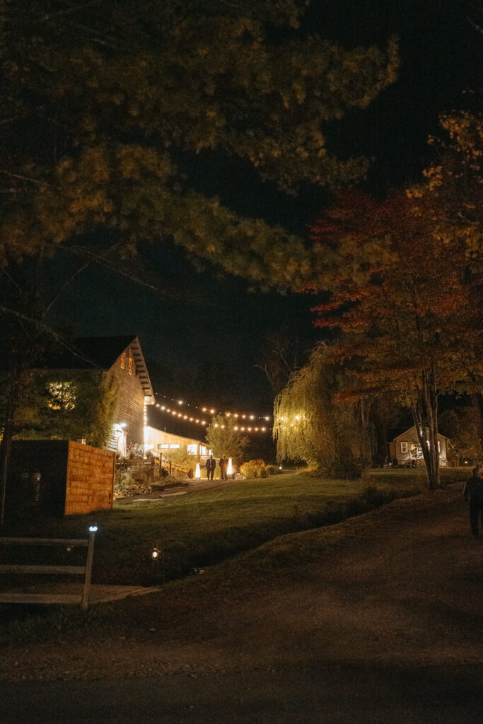 Farmhouse glowing at night beyond a dark lawn