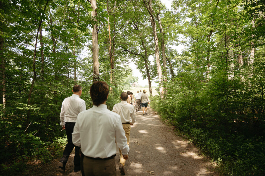 Guests walking ahead on a wooded path, seen from behind