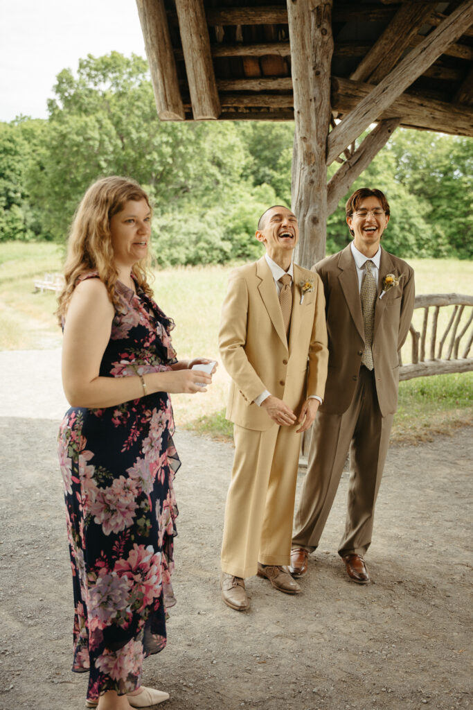 Guest in a navy floral dress laughing with the people in tan and taupe suits