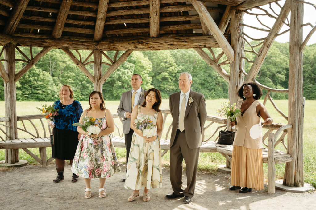 Guests waiting under the gazebo, some holding bouquets