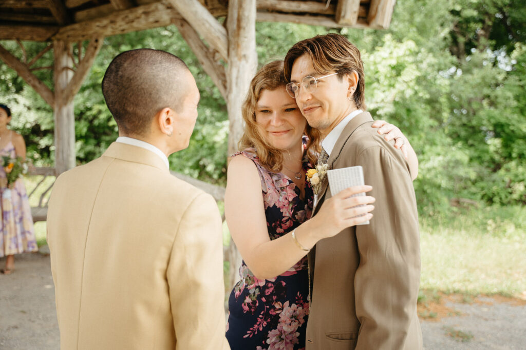 Guest in a floral dress hugging the person in a taupe suit