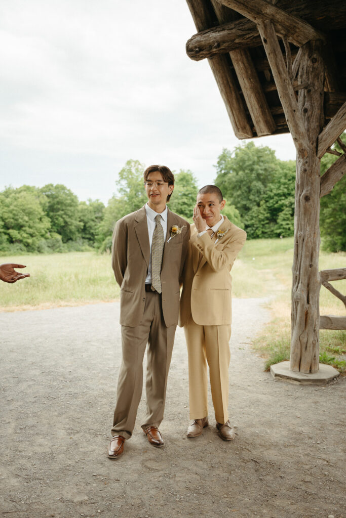 People in taupe and tan suits standing at the gazebo, one covering their mouth with a hand