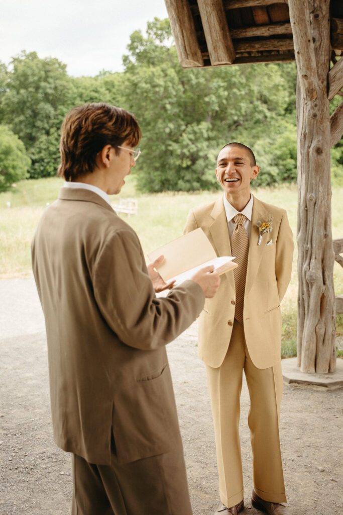 Person in a taupe suit reading a paper while the person in a tan suit laughs