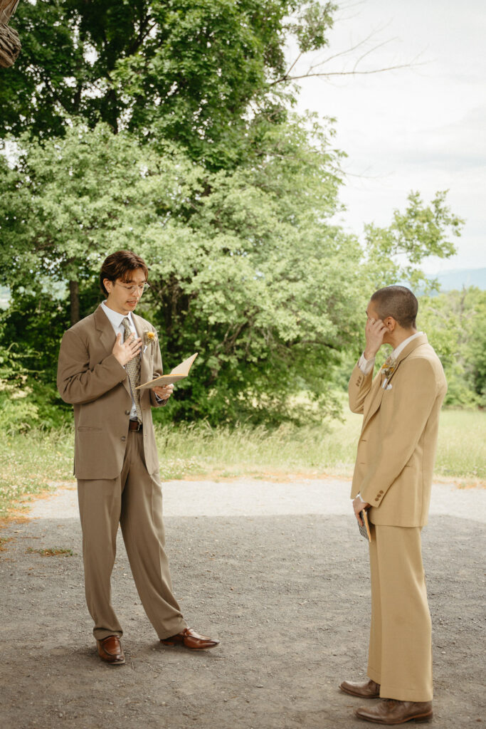 Person in a tan suit wiping their eye while the person in a taupe suit reads