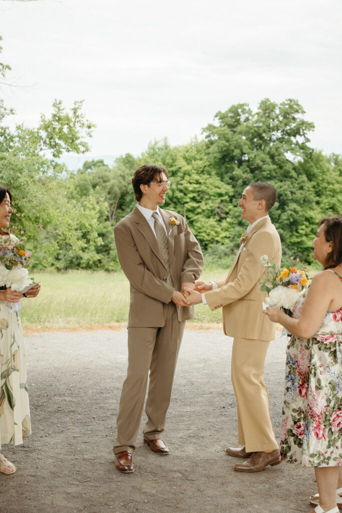 Couple holding hands and facing each other with guests behind them