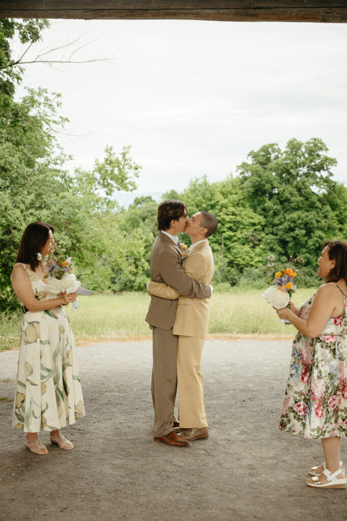 Couple kissing as two guests in floral dresses watch