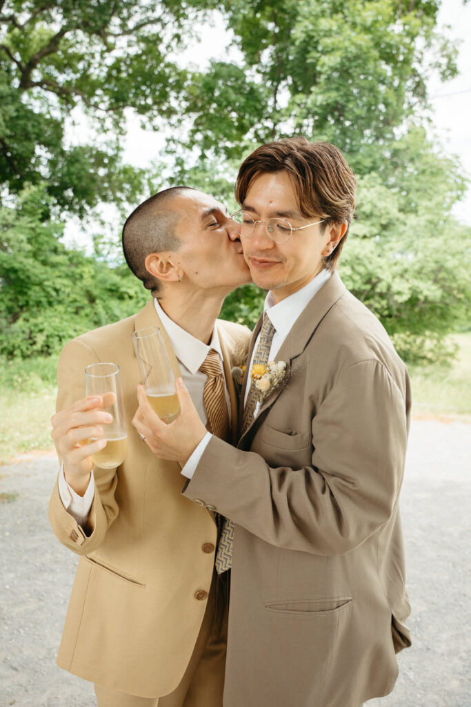 Couple kissing each other on the cheek, each holding a glass