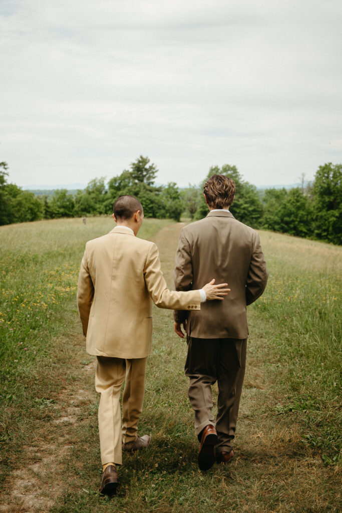 Couple walking away across the meadow, one with an arm on the other's back
