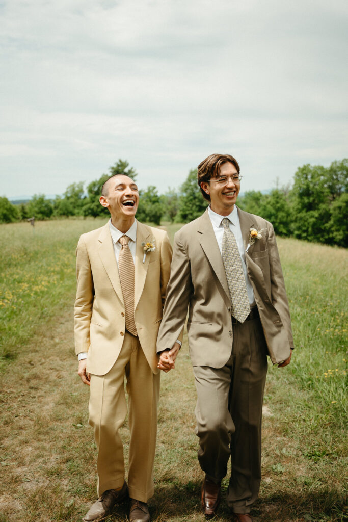 Couple laughing as they walk hand in hand through the meadow