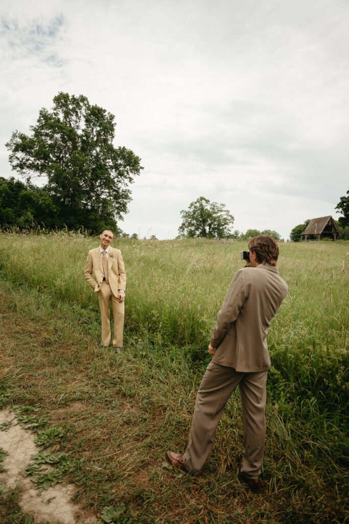 Person in a taupe suit photographing the person in a tan suit in a meadow