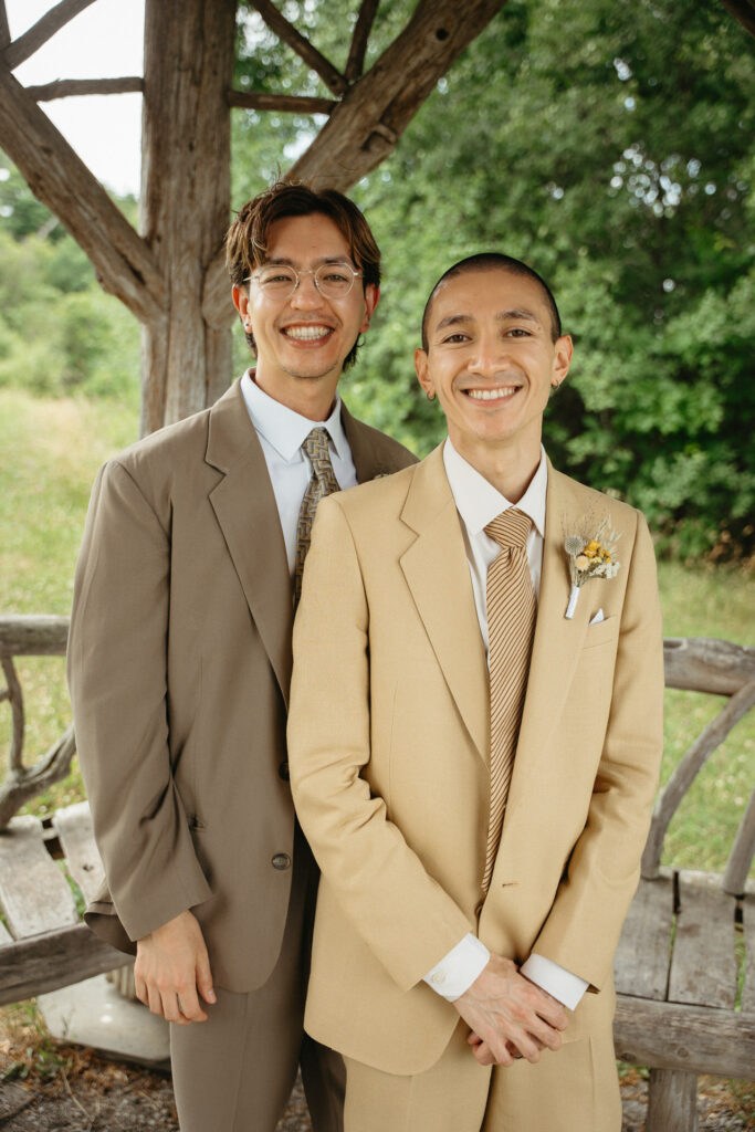 Couple smiling close together at the gazebo, leaning on a bench