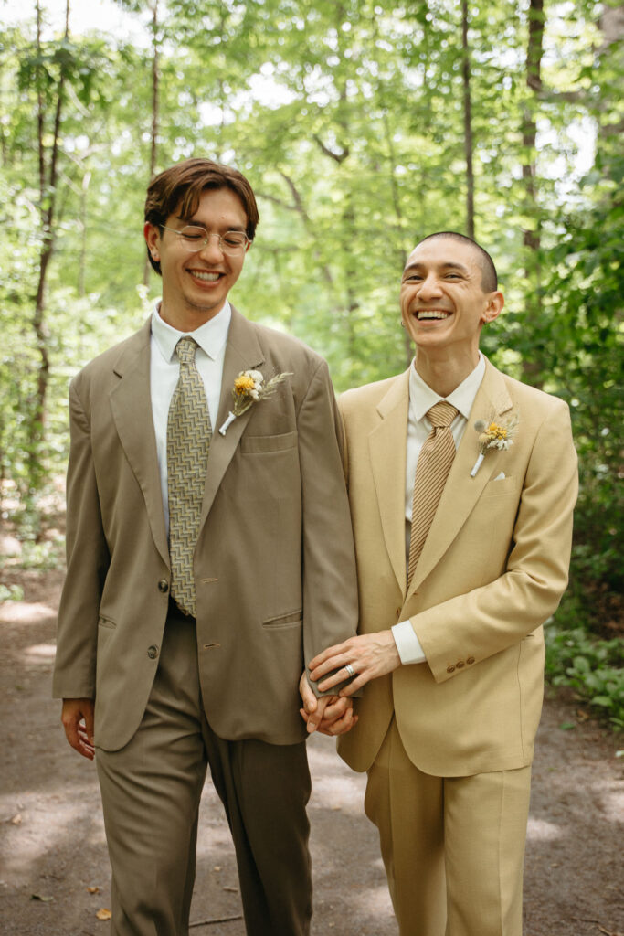 Couple laughing and walking hand in hand on a wooded path