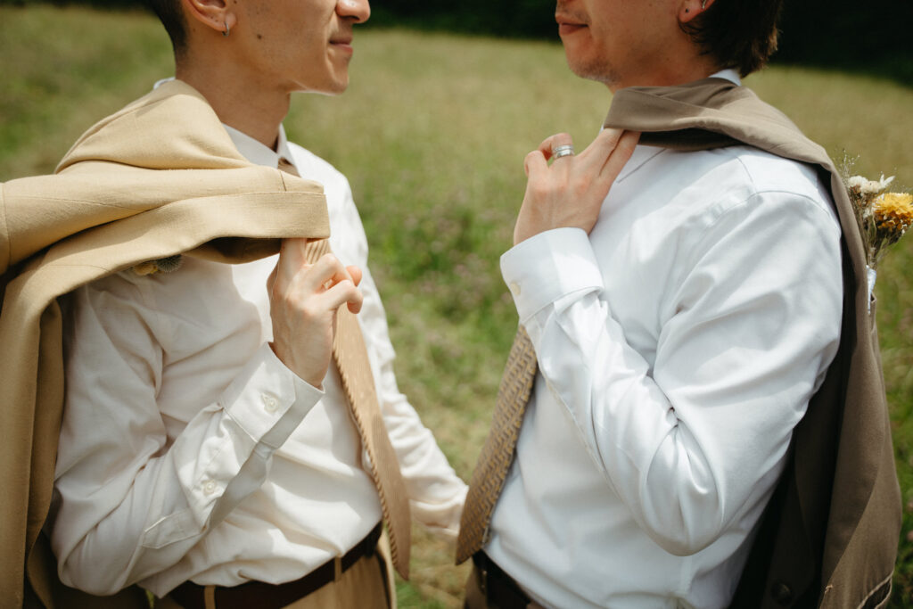 Close-up of two people adjusting suit jackets draped over their shoulders